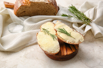 Slices of fresh bread with butter and rosemary on light background