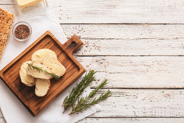 Fototapeta na wymiar Slices of fresh bread with butter, flax seeds and rosemary on light wooden background