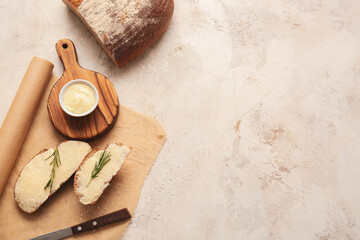 Fototapeta na wymiar Slices of fresh bread with butter and rosemary on light background