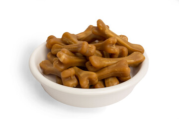 Close-up of brown bones of dog food, in a white food bowl, on a white studio background.