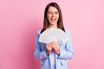 Photo portrait of winking girl holding cash fan in two hands isolated on pastel pink colored...