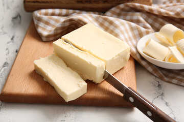 Board with fresh butter on light background, closeup