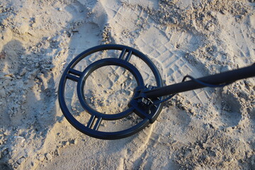 Metal detector coil looking for a treasure on sand