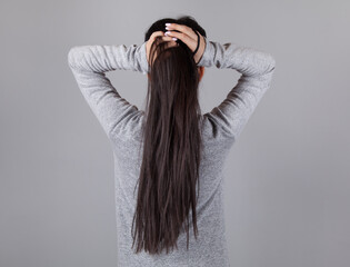 Young woman tie hair. Gray background.