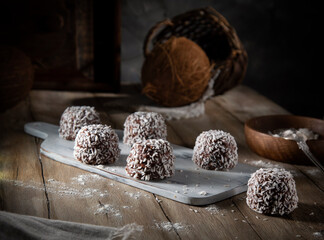 Chocolate balls with coconut flakes on a rustic table