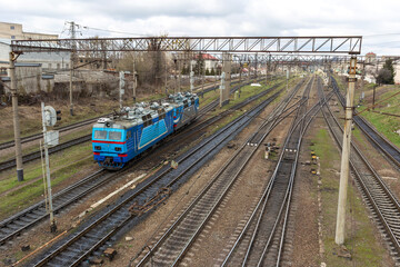 The blue electric locomotive maneuvers on the railway tracks.
