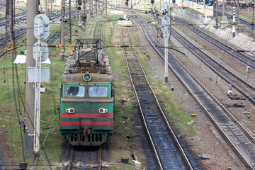 The green electric locomotive maneuvers on the railway tracks.