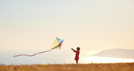 happy child girl launches a kite at sunset outdoors