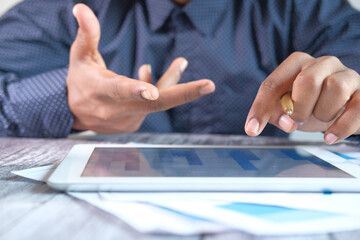 man's hand working on digital tablet at office desk, using self created chart 