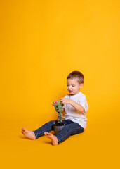 a child in jeans and a white T-shirt looks at a cactus in a pot