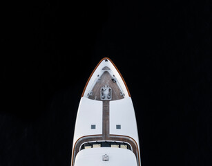 High angle aerial bird's eye partial view of the bow of a long white luxury yacht with wooden deck...