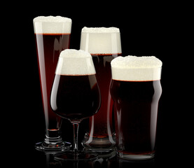 Set of fresh stout beer glasses with bubble froth isolated on black background.