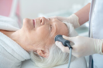 Beautician doing microcurrents therapy to an elderly customer