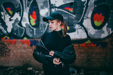 a girl in a black hipster baseball cap on the background of graffiti