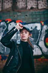 Obraz na płótnie Canvas a girl in a black hipster baseball cap on the background of graffiti