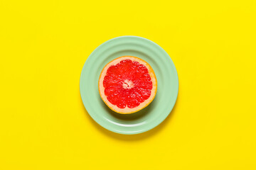 Plate with slice of ripe grapefruit on color background