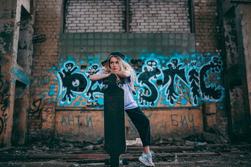 hipster girl in an abandoned building with a skateboard in her hands, graffiti