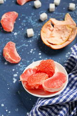 Bowl with slices of ripe grapefruit and sugar on color background