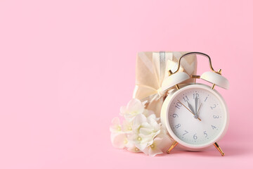 Composition with alarm clock and gift box on color background