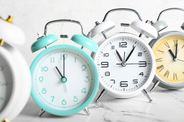 Different alarm clocks on light background, closeup