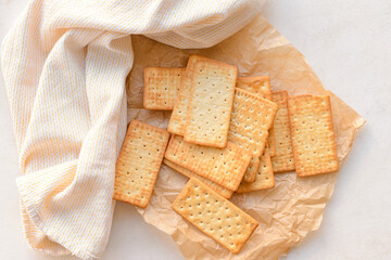 Parchment paper with crackers on light background
