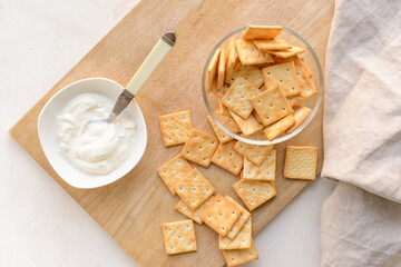 Bowl of tasty crackers and sauce on table