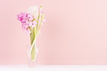 Soft light exquisite pink hyacinth flowers in glass vase on white wood table, romantic springtime background.