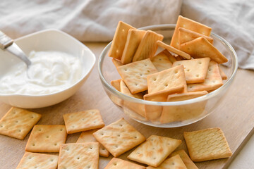 Bowl of tasty crackers and sauce on table