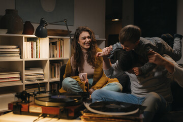 family having fun at home. they are listening to a music on record player
