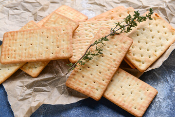 Parchment paper with crackers on color background
