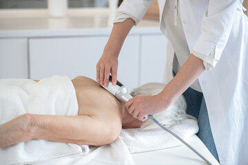 Female massage therapist doing back massage procedures to a woman