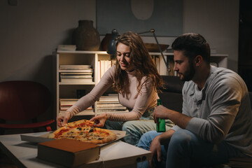 romantic couple eating pizza at home. moody evening atmosphere