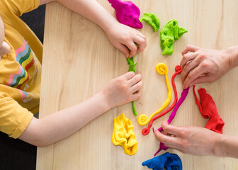 Child hands playing with colorful clay. Homemade plastiline. Activities for children in quarantine. Girl sculpts from plasticine at home on isolation. Coronavirus 2021.