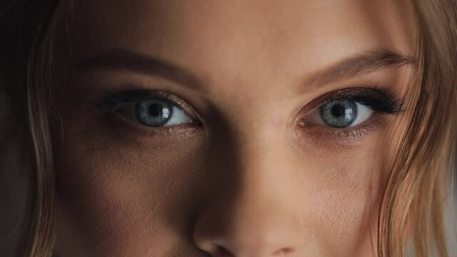 Young beautiful caucasian woman opens blue eyes close up macro human iris natural beauty