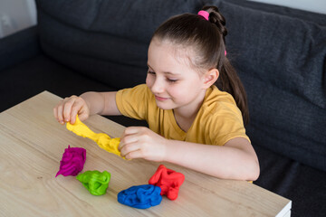 Child playing with colorful clay. Homemade plastiline. Activities for children in quarantine. Girl sculpts from plasticine at home on isolation. Coronavirus 2021.