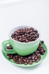 cup of coffee, close-up of a green ceramic cup with white inside, on a plate with coffee beans on a white surface, vertical photo
