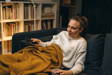 young woman relaxing on couch and watching television at her home