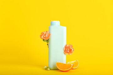 Shower gel, orange slices and flowers on color background