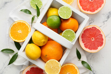 Basket with fresh citrus fruits on light background
