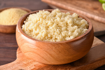 Bowl with tasty couscous on wooden background, closeup