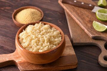 Bowl with tasty couscous on wooden background