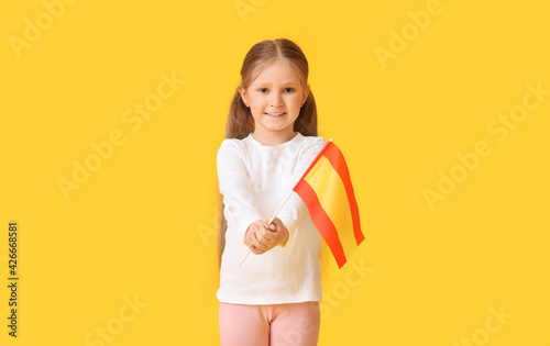 Little girl with the flag of Spain on color background