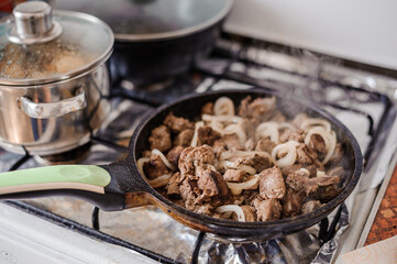 Fried veal liver with onions in a pan. Braised cow and pork liver