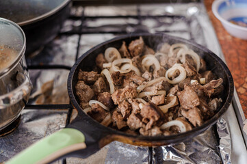 Fried veal liver with onions in a pan. Braised cow and pork liver