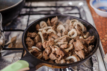 Fried veal liver with onions in a pan. Braised cow and pork liver