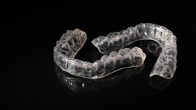Transparent removable braces swirls around on a black background