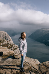 Naklejka premium A pretty girl stands on top of Mount Preikestolen (Pulpit Rock) in Norway