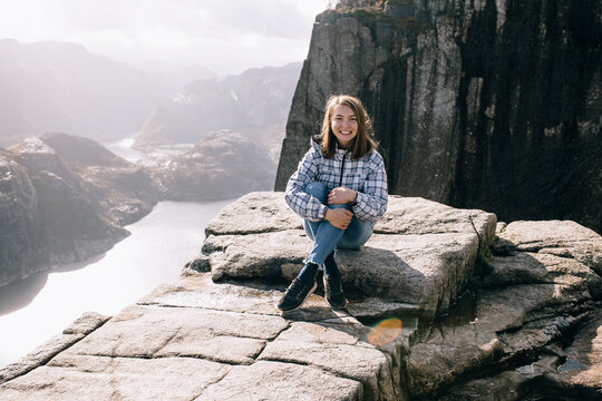 A Pretty Girl Sits On Top Of Mount Preikestolen (Pulpit Rock) In Norway