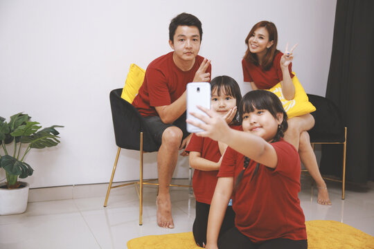 Smiling young family with two little daughters make self-portrait picture on cell together, happy parents with small children have fun take selfie on smartphone at home