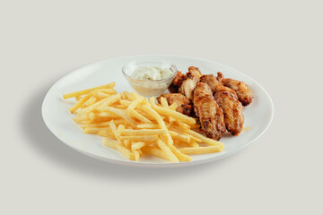 Chicken wings with french fries and garlic mayonnaise and sweet and sour sauce.